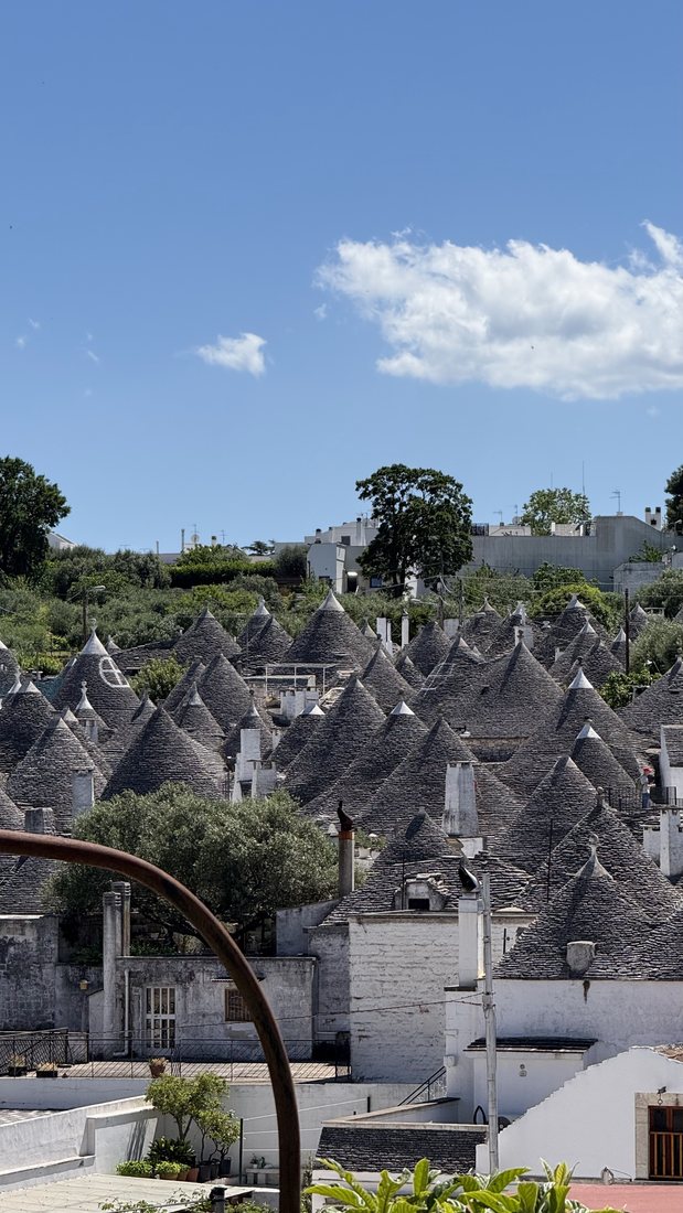 Cone-roofed trulli houses under a blue sky